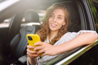 Güzel bayan sürücü arabada akıllı telefon kullanır. Araba kullanan bir kadın park ücretini ödemek ve şehirde dolaşmak için cep telefonu kullanıyor..