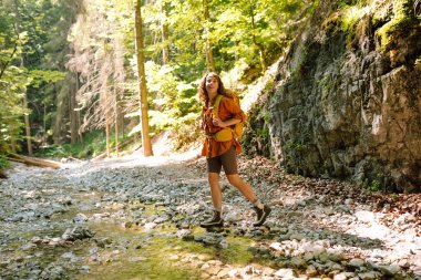 Bir gezgin, güneşli bir günde, dağlarda yürüyüş parkurunda dağın arka planına karşı yürür. Yürüyüş, aktif yaşam tarzı. Açık hava eğlencesi konsepti.