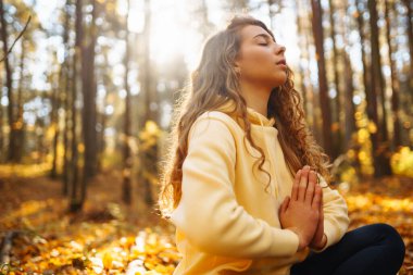 Spor giyim sektöründe aktif bir kadın sonbahar ormanında düşen yapraklar üzerinde yoga egzersizleri yapıyor, zen, meditasyon, rahatlama yapıyor. Rahatlama, özgürlük kavramı..