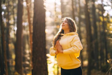 Spor giyim sektöründe aktif bir kadın sonbahar ormanında düşen yapraklar üzerinde yoga egzersizleri yapıyor, zen, meditasyon, rahatlama yapıyor. Rahatlama, özgürlük kavramı..