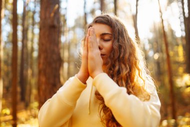 Spor giyim sektöründe aktif bir kadın sonbahar ormanında düşen yapraklar üzerinde yoga egzersizleri yapıyor, zen, meditasyon, rahatlama yapıyor. Rahatlama, özgürlük kavramı..