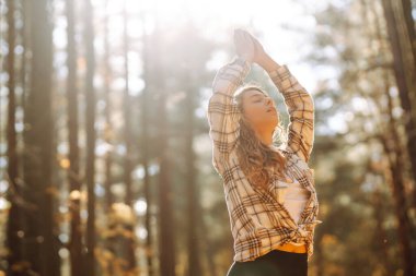 Spor giyim sektöründe aktif bir kadın sonbahar ormanında düşen yapraklar üzerinde yoga egzersizleri yapıyor, zen, meditasyon, rahatlama yapıyor. Rahatlama, özgürlük kavramı..