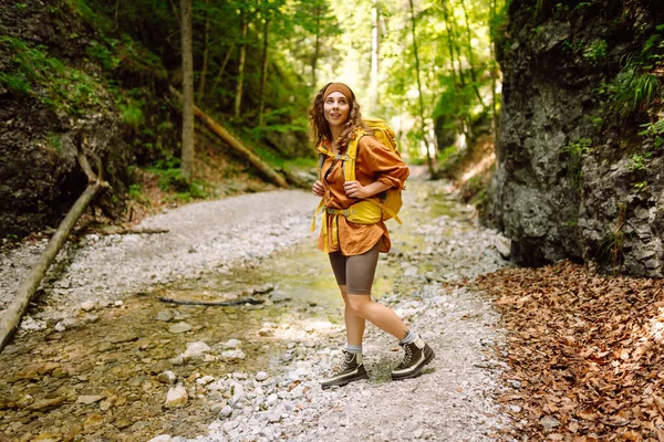 stock image A traveler walks along a forest hiking trail in the mountains against the backdrop of mountain nature on a sunny day. Hiking, active lifestyle. Outdoor recreation concept.