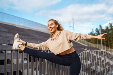 Spor giyim sektöründe aktif bir kadın esneme egzersizi yapıyor. Smartwatch 'ten fitness uygulamasına bakıyor. Spor, eğitim veya aktif yaşam tarzı kavramı.