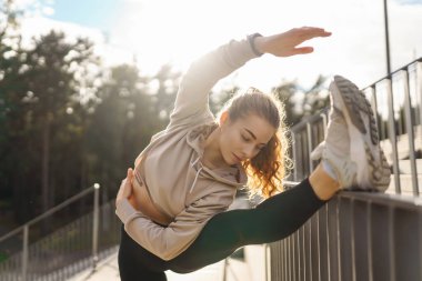 Spor giyim sektöründe aktif bir kadın esneme egzersizi yapıyor. Smartwatch 'ten fitness uygulamasına bakıyor. Spor, eğitim veya aktif yaşam tarzı kavramı.