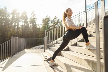 Spor giyim sektöründe aktif bir kadın esneme egzersizi yapıyor. Smartwatch 'ten fitness uygulamasına bakıyor. Spor, eğitim veya aktif yaşam tarzı kavramı.