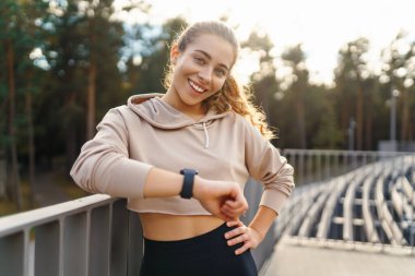 Spor giyim sektöründe aktif bir kadın esneme egzersizi yapıyor. Smartwatch 'ten fitness uygulamasına bakıyor. Spor, eğitim veya aktif yaşam tarzı kavramı.