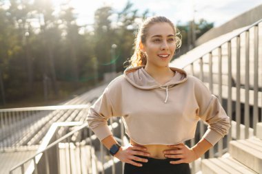 Spor giyim sektöründe aktif bir kadın esneme egzersizi yapıyor. Smartwatch 'ten fitness uygulamasına bakıyor. Spor, eğitim veya aktif yaşam tarzı kavramı.