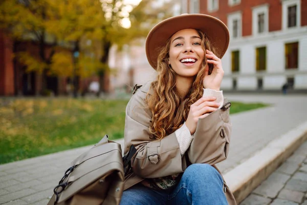 Seorang Wanita Bahagia Dengan Pakaian Santai Dan Topi Duduk Jalan — Stok Foto