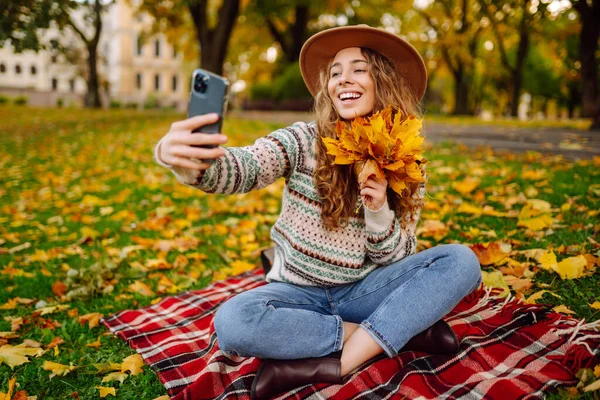 Uma Mulher Alegre Chapéu Senta Cobertor Parque Outono Com Telefone — Fotografia de Stock