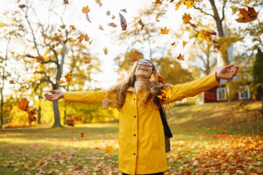 Sonbahar sarı yaprakları atan güzel bir kadın. Mutlu bayan turist sonbahar parkında eğleniyor ve doğanın tadını çıkarıyor. Rahatlama, eğlence, doğa ile yalnızlık kavramı..