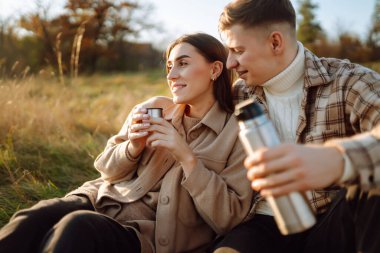 Genç bir erkek ve kadın sonbahar ormanlarında birlikte vakit geçirir, termostan sıcak bir içecek içer, yürür, doğanın tadını çıkarırlar. Tatil, doğada hafta sonu.