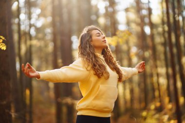 Aktif kadın, sonbahar ormanında sarı yaprakların arasında yoga yapıyor. Zen 'e yakalanıyor. Meditasyon kavramı, rahatlama. Etkin yaşam biçimi.