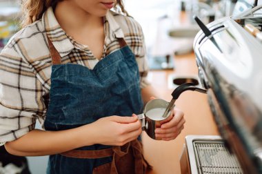 Deneyimli bir bayan barmen sıcak bir içecek hazırlar. Barın arkasında önlüklü bir kadın taze kahve hazırlıyor. Paket yemek. Profesyonel kahve yapma..