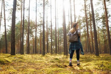 Sırt çantalı şapkalı güzel bir kadın doğa yürüyüşüne çıkmış. Bir gezgin sonbahar ormanında havanın tadını çıkararak yürür. Etkin yaşam biçimi.