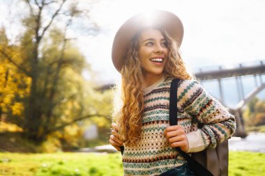 Sırt çantalı şapkalı güzel bir kadın doğa yürüyüşüne çıkmış. Bir gezgin sonbahar ormanında havanın tadını çıkararak yürür. Etkin yaşam biçimi.