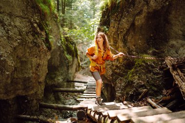Parlak sırt çantalı bir kadın gezgin yürüyüş parkurunda dağların içinden geçiyor. Maceralar. Doğa kavramı ve aktif yaşam tarzı.