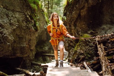 Parlak sırt çantalı bir kadın gezgin yürüyüş parkurunda dağların içinden geçiyor. Maceralar. Doğa kavramı ve aktif yaşam tarzı.