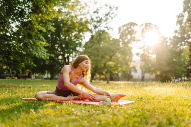 İnanılmaz genç ve güzel bir kadın parkta yoga ve meditasyon egzersizi yapıyor. Spor yaşam tarzı. Fitness