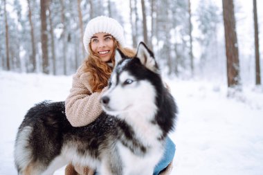 Güzel genç bir kadın kış ormanında köpeğiyle oynar. İlk kar. Arkadaşlık, sevgi ve bağlılık kavramı. Açık hava eğlencesi