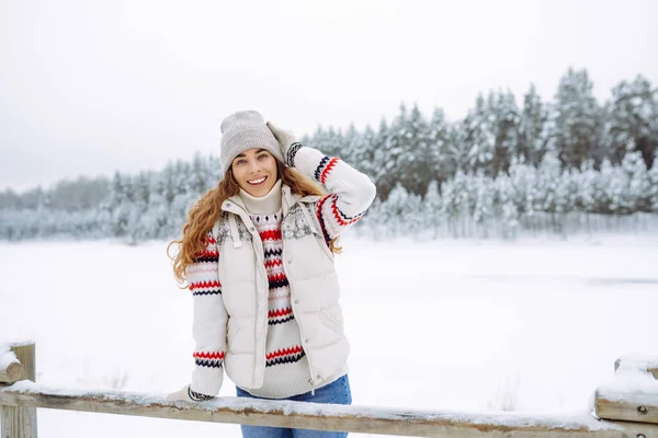 Smiling woman walks near a winter lake. She is enjoying the beautiful winter weather. Winter walk concept