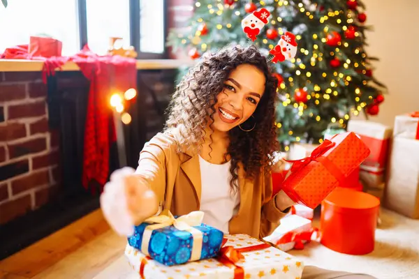 Yeni yıl ağacının yanında elinde maytap ve Noel hediyeleri tutan mutlu bir kadın. Tatil konsepti. Kış tatili.