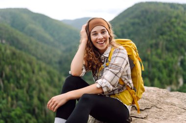 Sarı sırt çantalı aktif bir kadın dağlarda dolaşıyor. Genç bir gezgin bir Slovak trolünün tadını çıkarıyor. Seyahat kavramı.