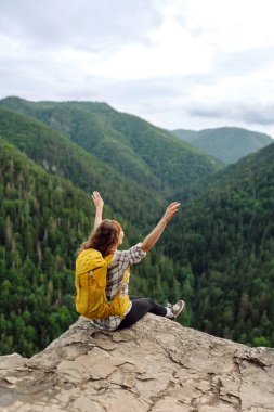 Sarı sırt çantalı aktif bir kadın dağlarda dolaşıyor. Genç bir gezgin bir Slovak trolünün tadını çıkarıyor. Seyahat kavramı.