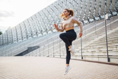 Atletik kadın dışarıda spor egzersizleri yapıyor. Özel giyinmiş genç bir bayan atlet sahada antrenman yapıyor. Spor anlayışı, sağlık.