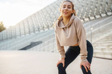 Atletik kadın dışarıda spor egzersizleri yapıyor. Özel giyinmiş genç bir bayan atlet sahada antrenman yapıyor. Spor anlayışı, sağlık.