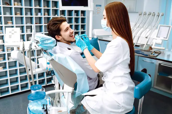 Smiling young man in the dentist's chair. A man in dentistry during a dental procedure. Healthy smile. Review of dental caries prevention.