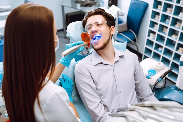 Smiling young man in the dentist\'s chair. A man in dentistry during a dental procedure. Healthy smile. Review of dental caries prevention.