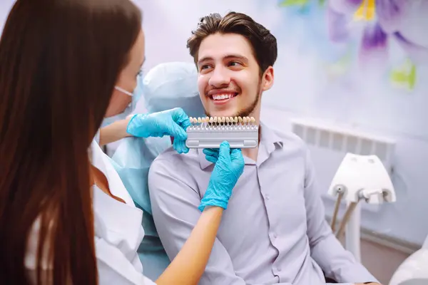 Smiling young man in the dentist\'s chair. A man in dentistry during a dental procedure. Healthy smile. Review of dental caries prevention.