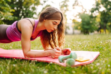 Yoga yapan genç bir kadın, parkta esneme hareketleri yapıyor. Spor giyim sektöründe güzel bir kadın açık havada antrenman yapıyor. Spor, spor konsepti.