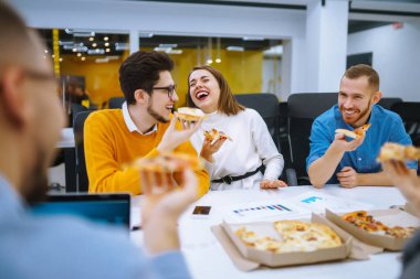 Ofiste bir mola sırasında birlikte pizza yiyen neşeli çeşitli çalışanlar. Ofisteki bir toplantıda genç insanlar kahve molası verdiler. İş kavramı, müzakereler.