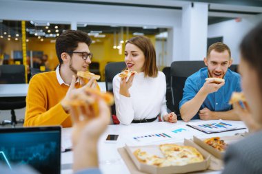 Ofiste bir mola sırasında birlikte pizza yiyen neşeli çeşitli çalışanlar. Ofisteki bir toplantıda genç insanlar kahve molası verdiler. İş kavramı, müzakereler.