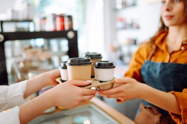 Bayan bir baristanın ellerinin yakın çekimi hazır içkileri uzatıyor. Barın arkasında bir kafe sahibi genç bir kadın kahve hazırlıyor. Sipariş verme kavramı.