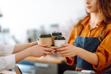 Bayan bir baristanın ellerinin yakın çekimi hazır içkileri uzatıyor. Barın arkasında bir kafe sahibi genç bir kadın kahve hazırlıyor. Sipariş verme kavramı.