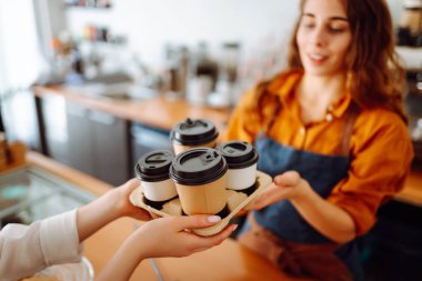 Bayan bir baristanın ellerinin yakın çekimi hazır içkileri uzatıyor. Barın arkasında bir kafe sahibi genç bir kadın kahve hazırlıyor. Sipariş verme kavramı.