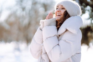 Karlı bir kış gününde dışarıda yürüyen mutlu bir kadın. Güzel bir kadın karlı bir parkta karla eğleniyor. Yürüme konsepti.