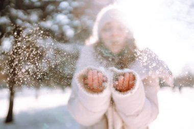 Karlı bir kış gününde dışarıda yürüyen mutlu bir kadın. Güzel bir kadın karlı bir parkta karla eğleniyor. Yürüme konsepti.