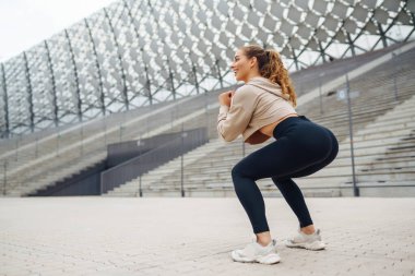 Atletik genç bayan dışarıda antrenman yapıyor. Spor salonundaki kadın dışarıda geriniyor. Aktif yaşam tarzı konsepti, spor.