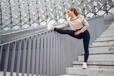 Atletik genç bayan dışarıda antrenman yapıyor. Spor salonundaki kadın dışarıda geriniyor. Aktif yaşam tarzı konsepti, spor.