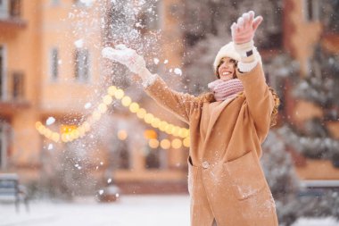 Karla eğlenen kalın elbiseli genç bir kadının Noel pazarının arka planına yakın çekimi. Tatil kavramı, eğlence.