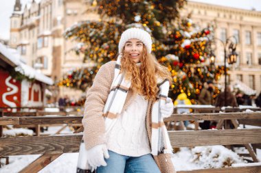 Eşarplı ve şapkalı gülümseyen kadın, bir panayırda eğleniyor, sıcak bir içki içiyor. Noel konsepti, kış tatili. Yaşam biçimi.