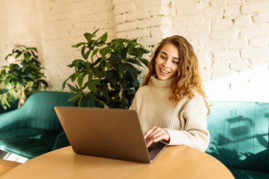 Genç bir kadın bir kafede otururken dizüstü bilgisayarla çalışıyor. Freelancer, modern bir kafede online olarak çalışıyor. Teknoloji kavramı, serbest çalışma. Yaşam biçimi.