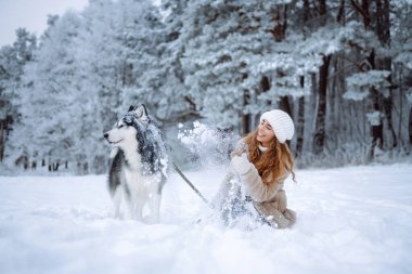 Şirin bir kadın kışın karlı ormanda köpeğiyle vakit geçirir. Mutlu köpek sahibi dışarıda birlikte eğleniyor. Eğlenceli bir konsept. Yaşam biçimi.