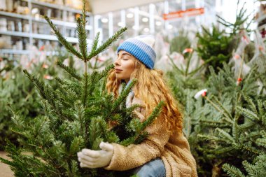 Parlak şapkalı mutlu kadın kış pazarında bir Noel ağacı satın alıyor. Genç bir kadın Noel 'in yaklaştığını hissediyor. Tatil kavramı, gelenekler.