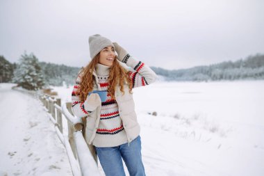 Güzel genç bir kadın termosla çay içer. Harika kış havası, karlı göl. Kış yürüyüşü. Genç bayan turist dışarıda havanın tadını çıkarıyor..