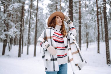 Kürk manto, eşarp ve kış ormanında poz veren güzel bir kadın. Açık havada poz veren mutlu bayan turist. Noel.